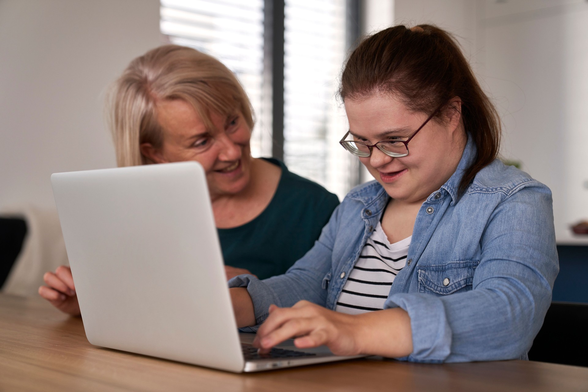 Down syndrome woman using computer with help of her mother