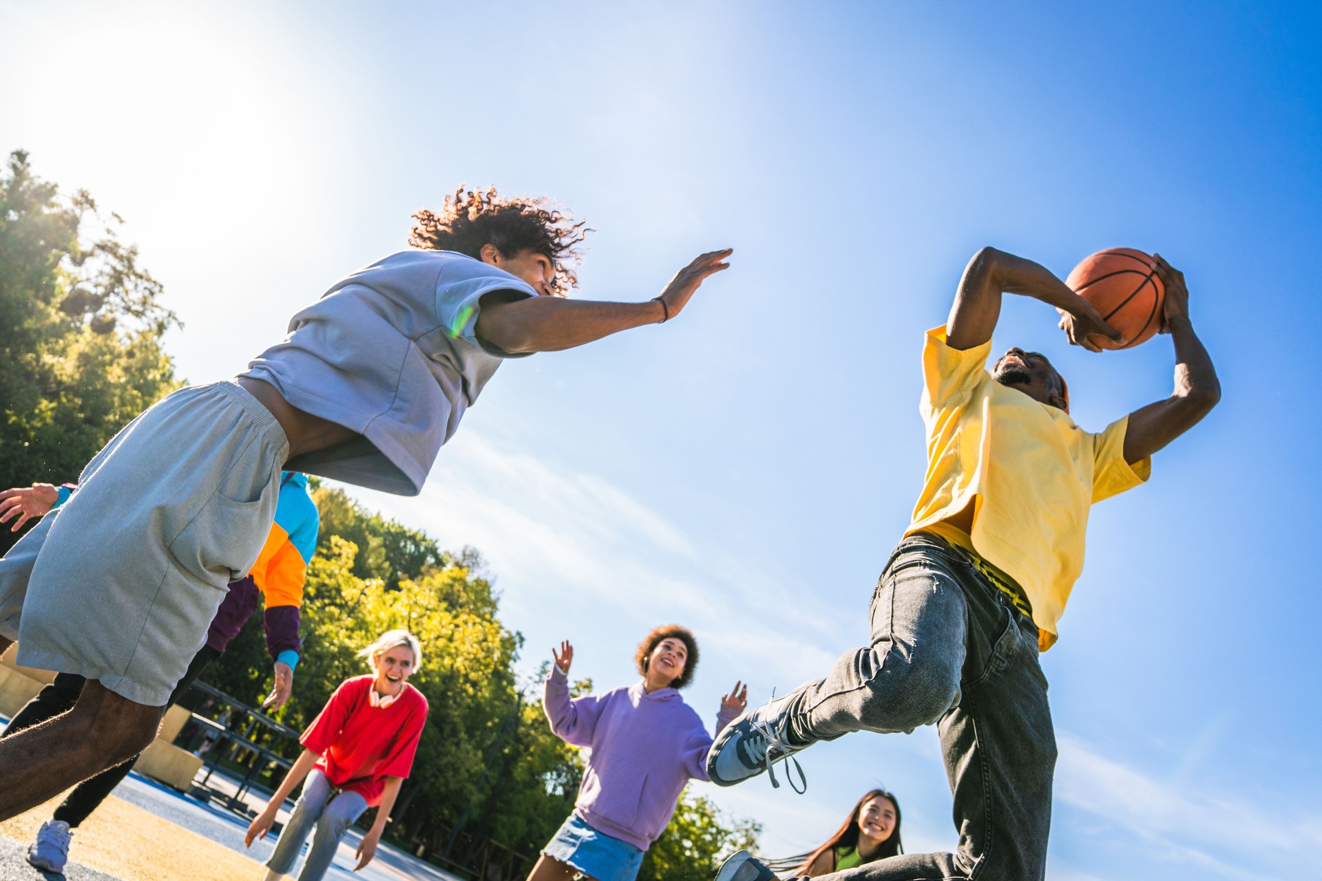 Low Angle View Of Friends Jumping Against Clear Sky